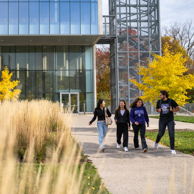 Two men stand outside, with one pointing to something in the distance.