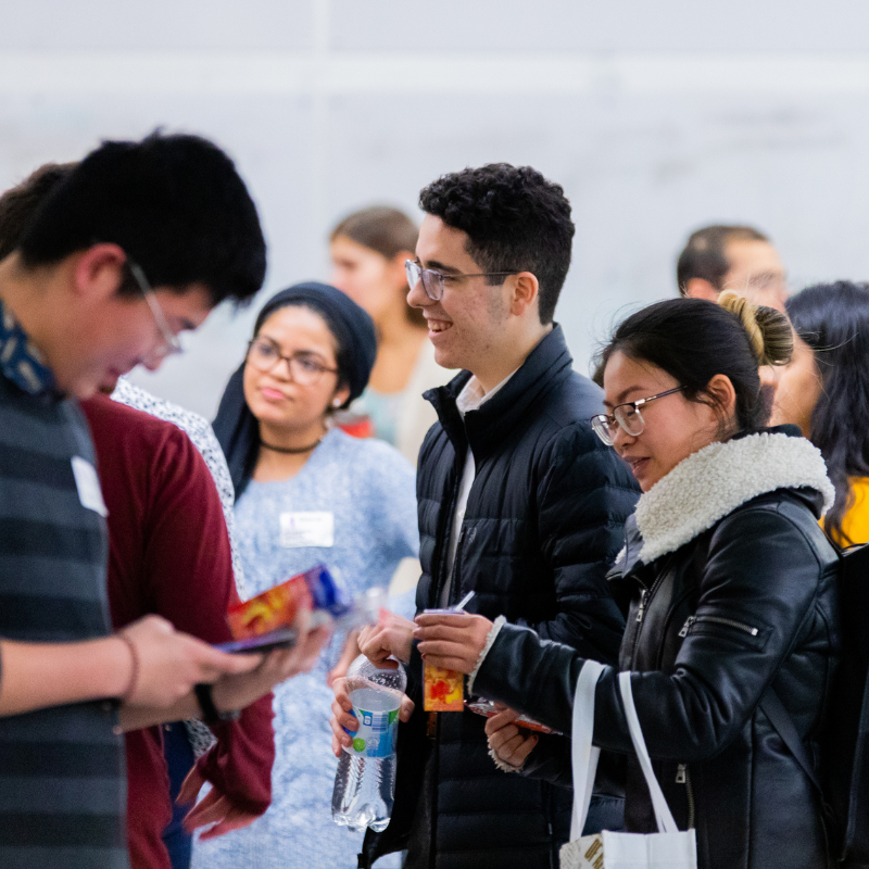 Two smiling young men stand in front of a shoe rack.