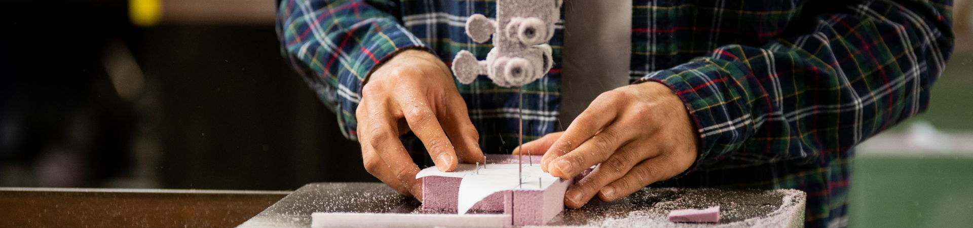 A pair of hands use a tool to cut styrofoam.