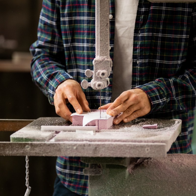 A pair of hands use a tool to cut styrofoam.