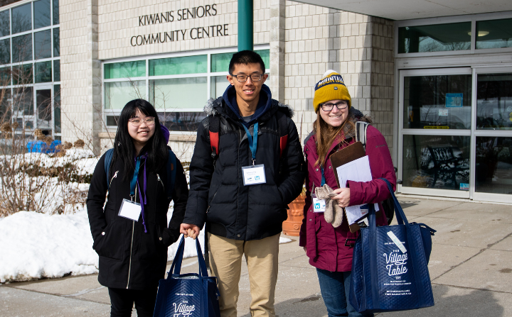 Three students stand in front of a community centre.