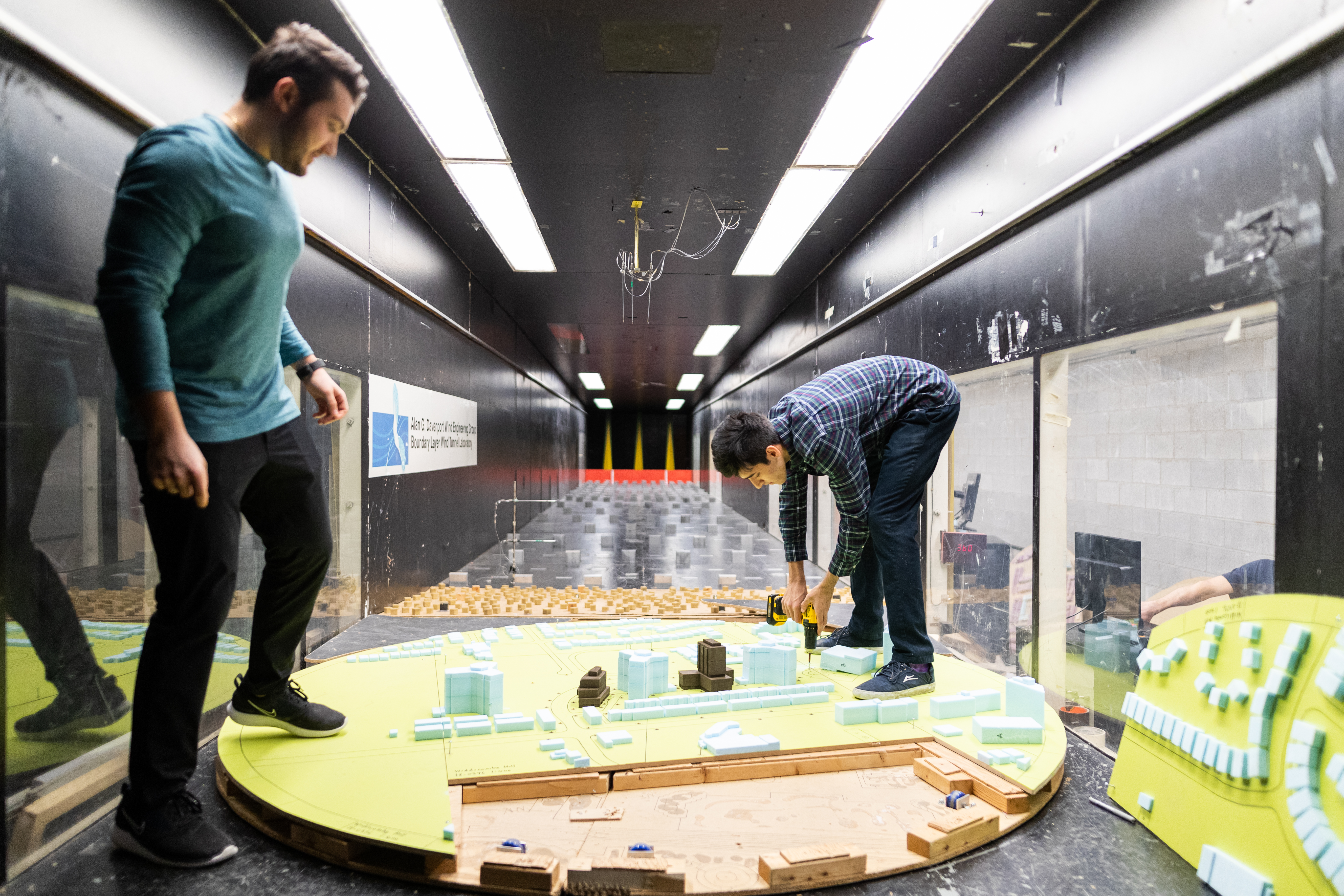 Two men stand around a model structure.