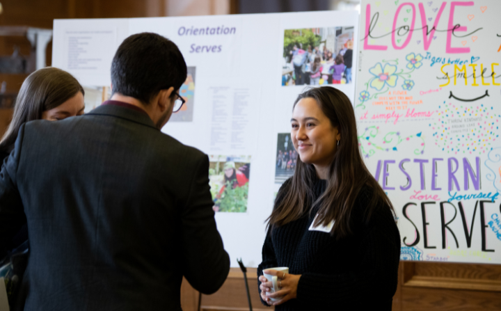 A young lady stands in front of a project poster.