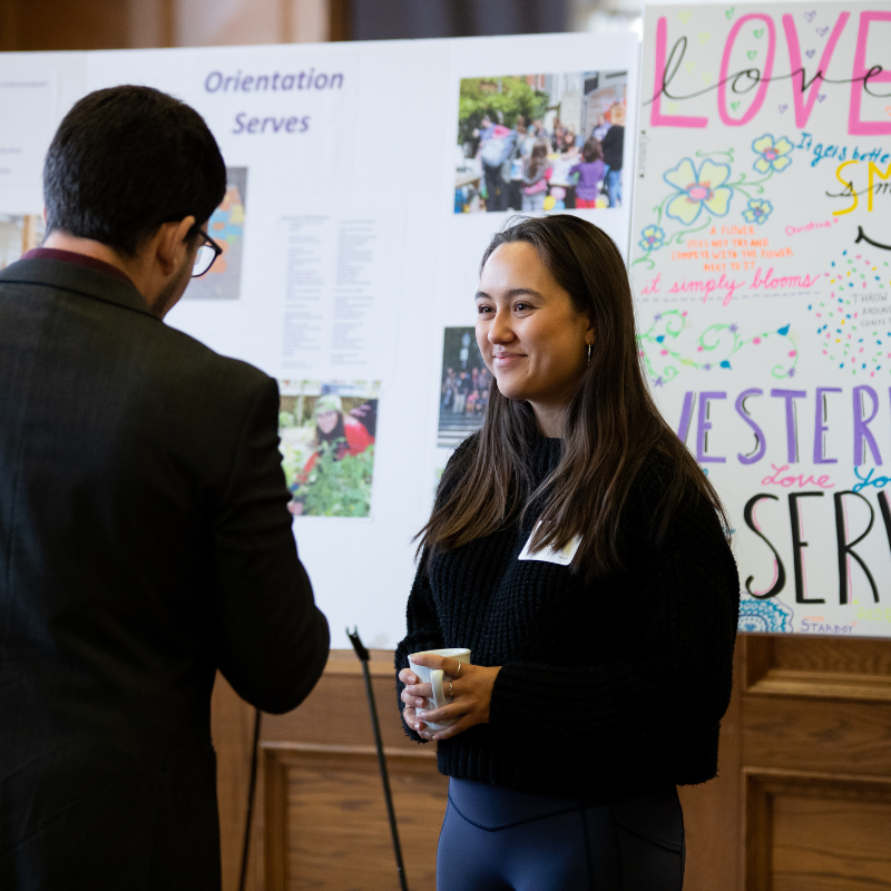 A smiling young woman stands in front of a poster board.
